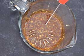 whisking the marinade ingredients together in a glass measuring cup.