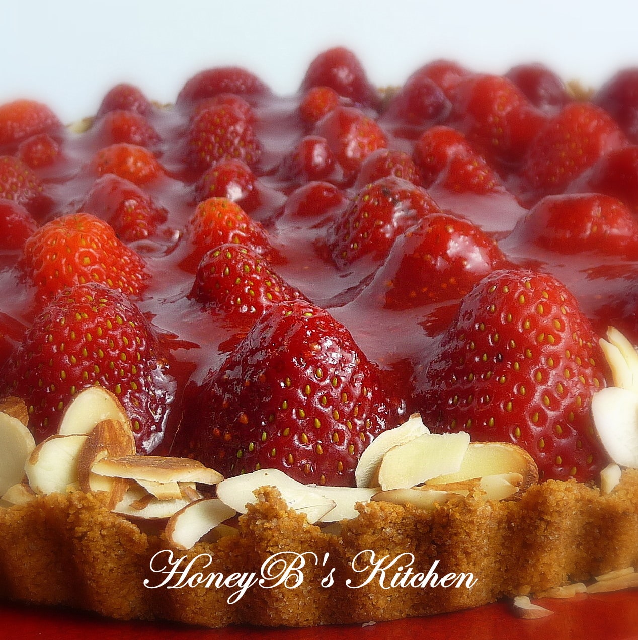 Side view of a strawberry pie in a graham cracker crust with sliced toasted almonds.