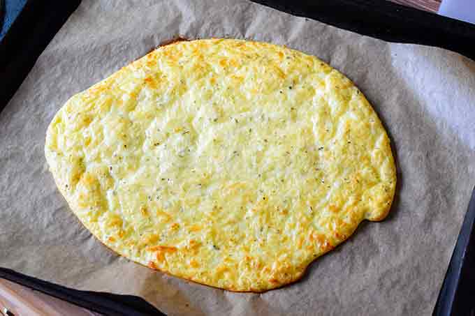 Baked cheese and egg crust on parchment paper without toppings.