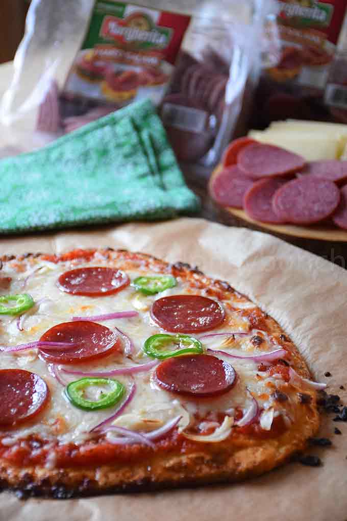 A baked Keto Salami Pizza on a cutting board.