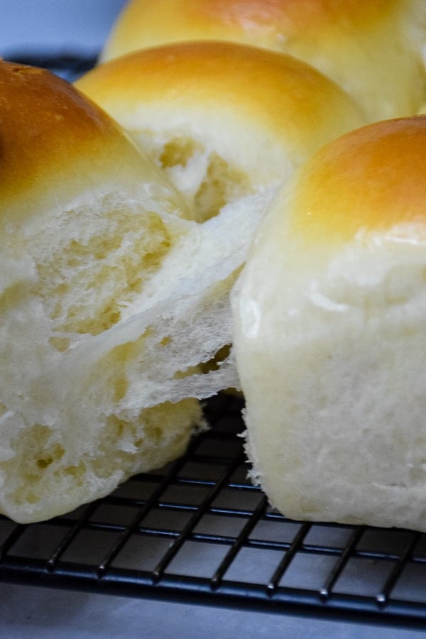 Upclose image of the dinner rolls being pulled apart and flakes of dough still connecting the rolls.
