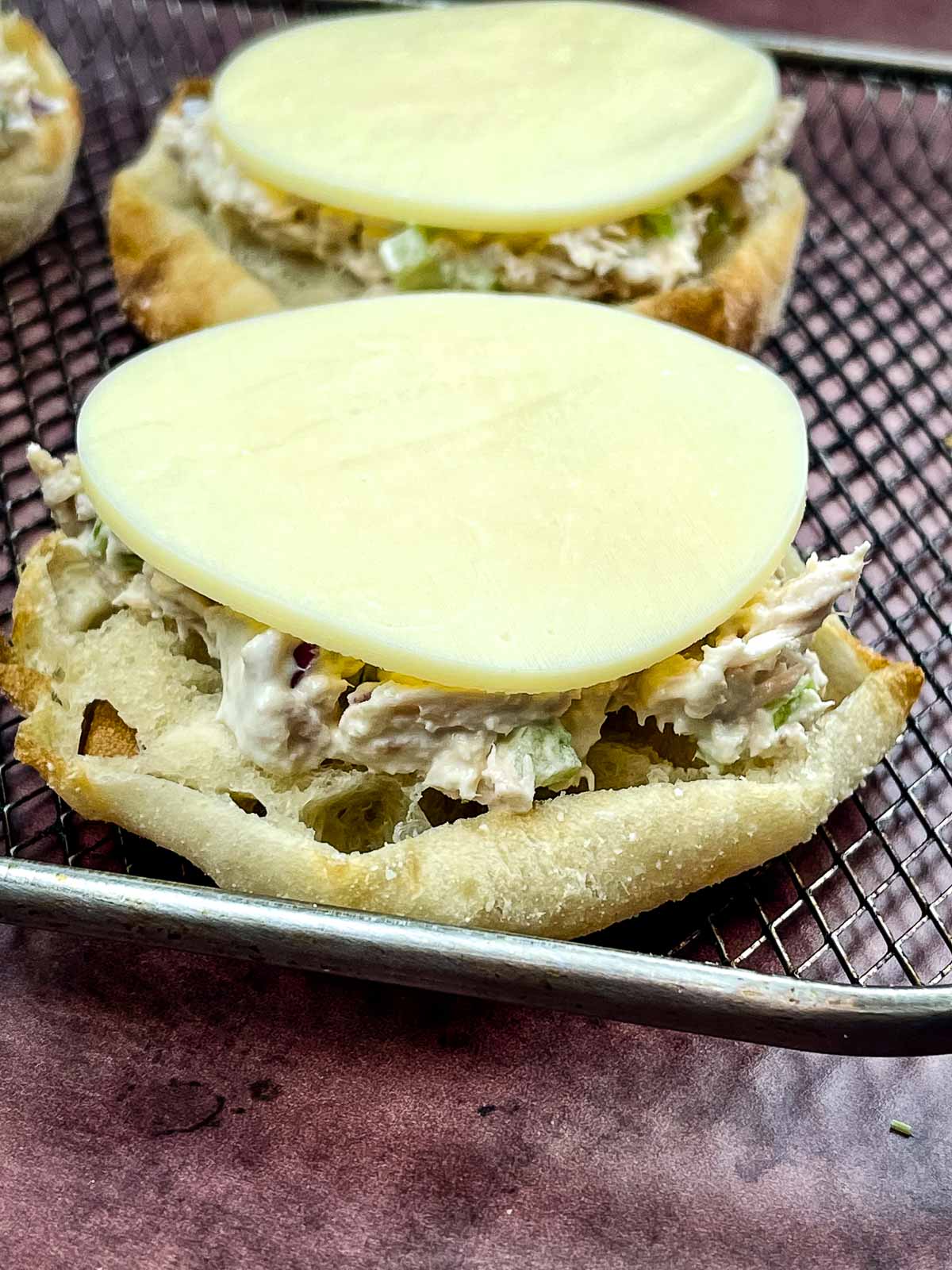 Provolone cheese on top of the open faced tuna melt.