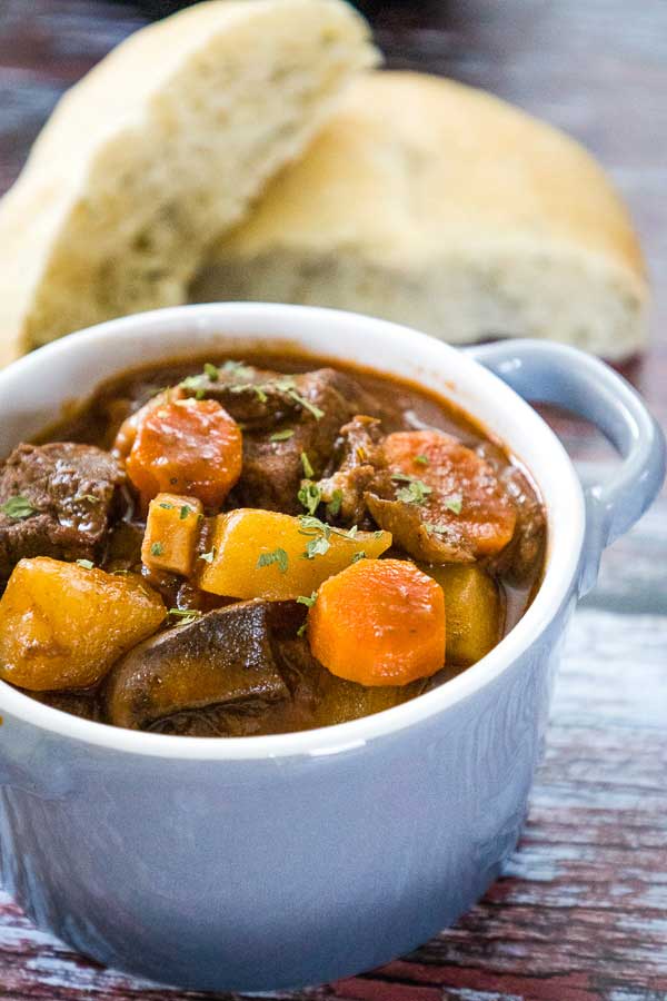 A gray bowl with pieces stew meat and veggies in a flavorful wine based broth.