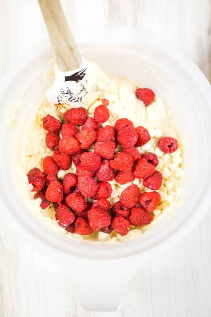 Raspberries and white chocolate chips on top of the muffin batter.