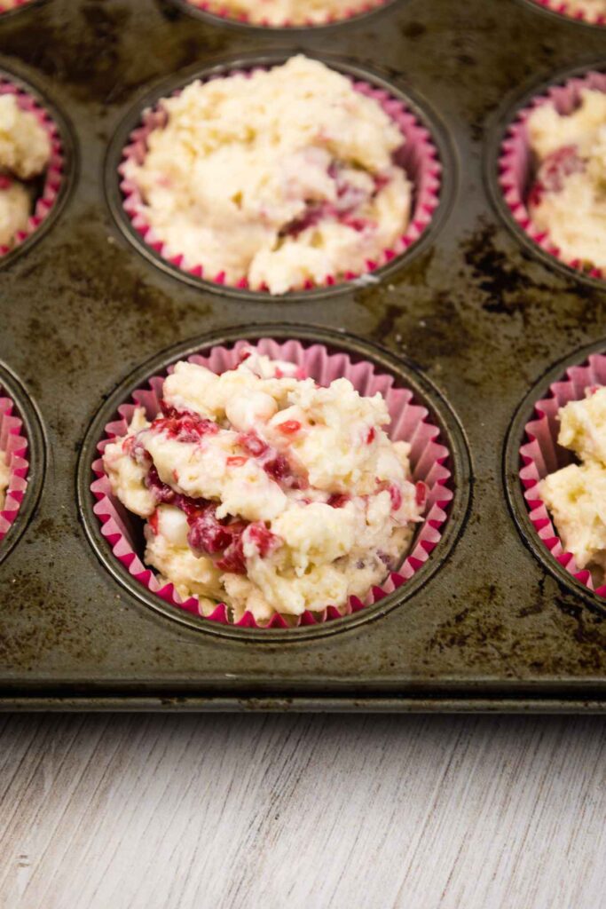 Muffin batter in paper cups in muffin tin.