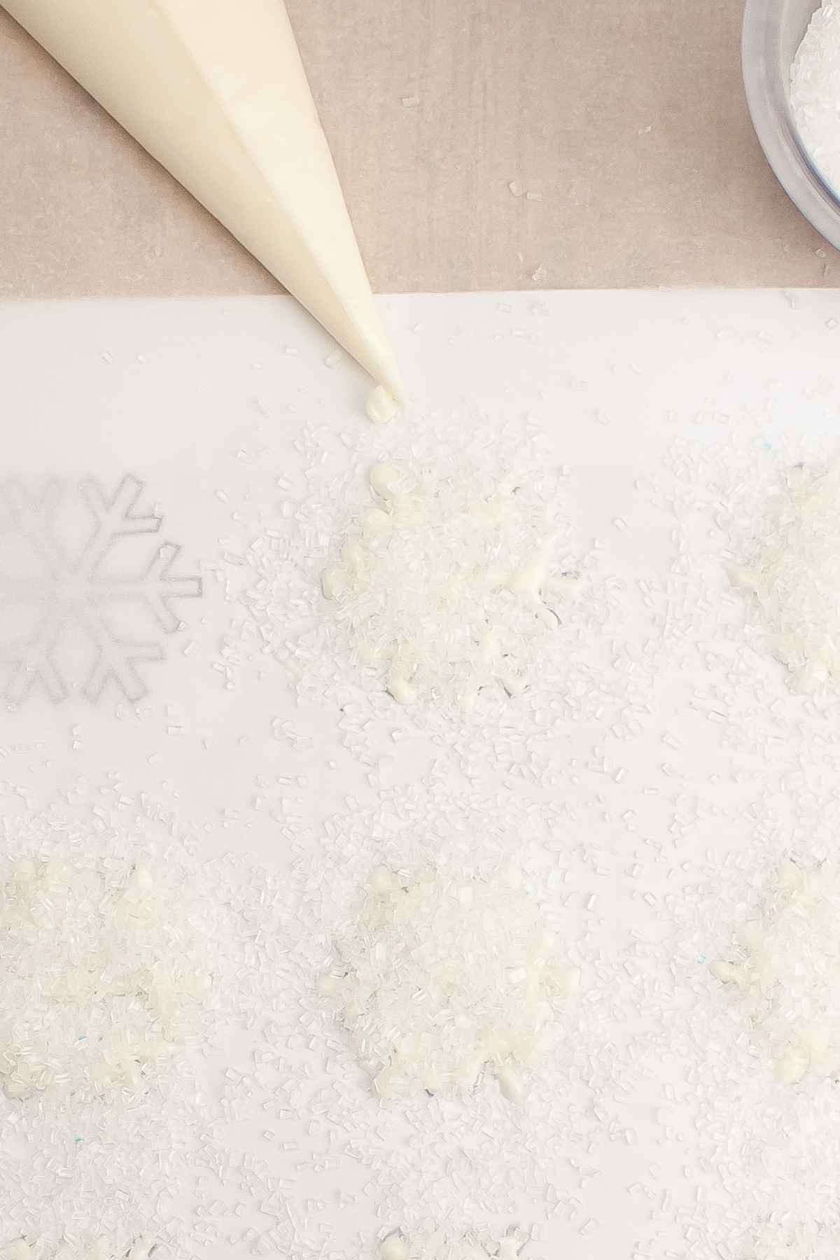 White chocolate stars on parchment paper and sparkly white sugar.