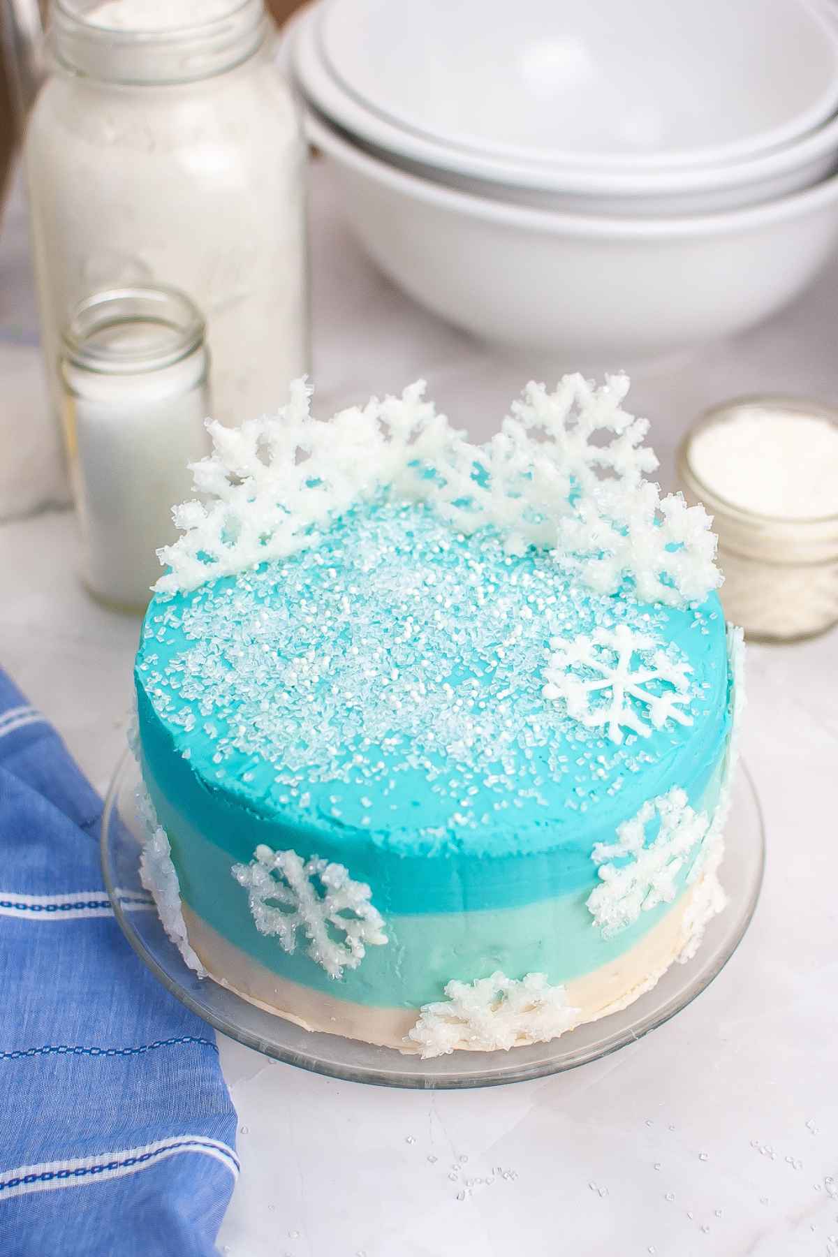 Angled image of winter wonderland cake with ombre blue frosting and sparkling white chocolate snowflakes.
