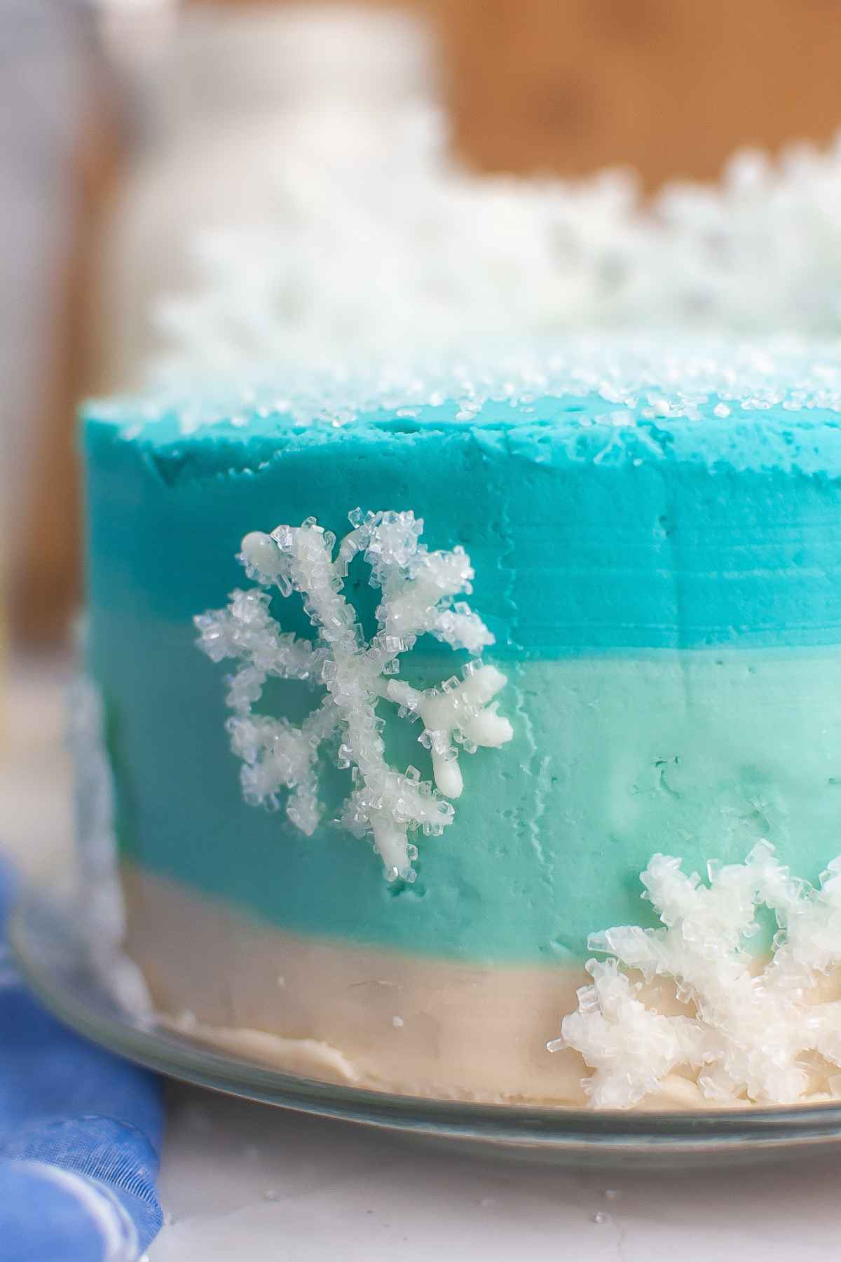 Up close image of winter wonderland cake with ombre blue frosting and sparkling white chocolate snowflakes.