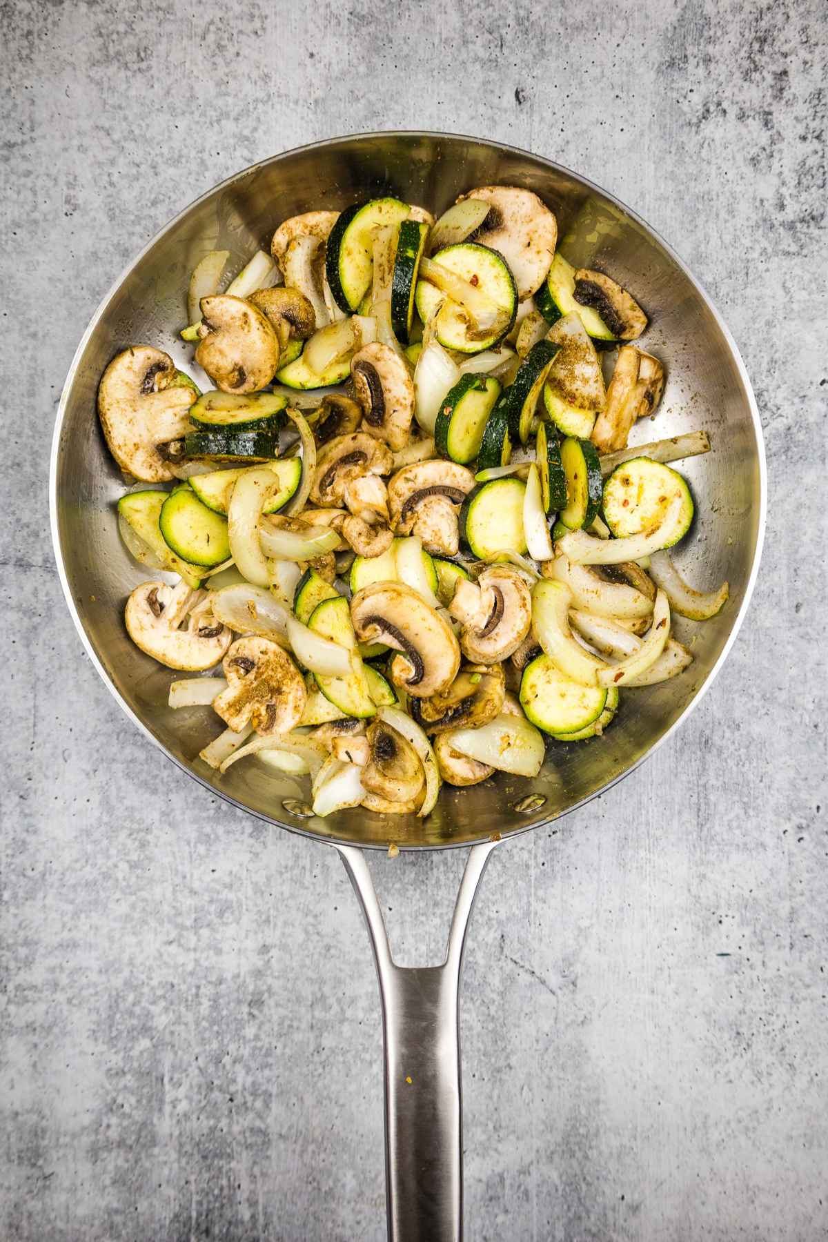 Veggies tossed with seasoning and partially cooked in a skillet.