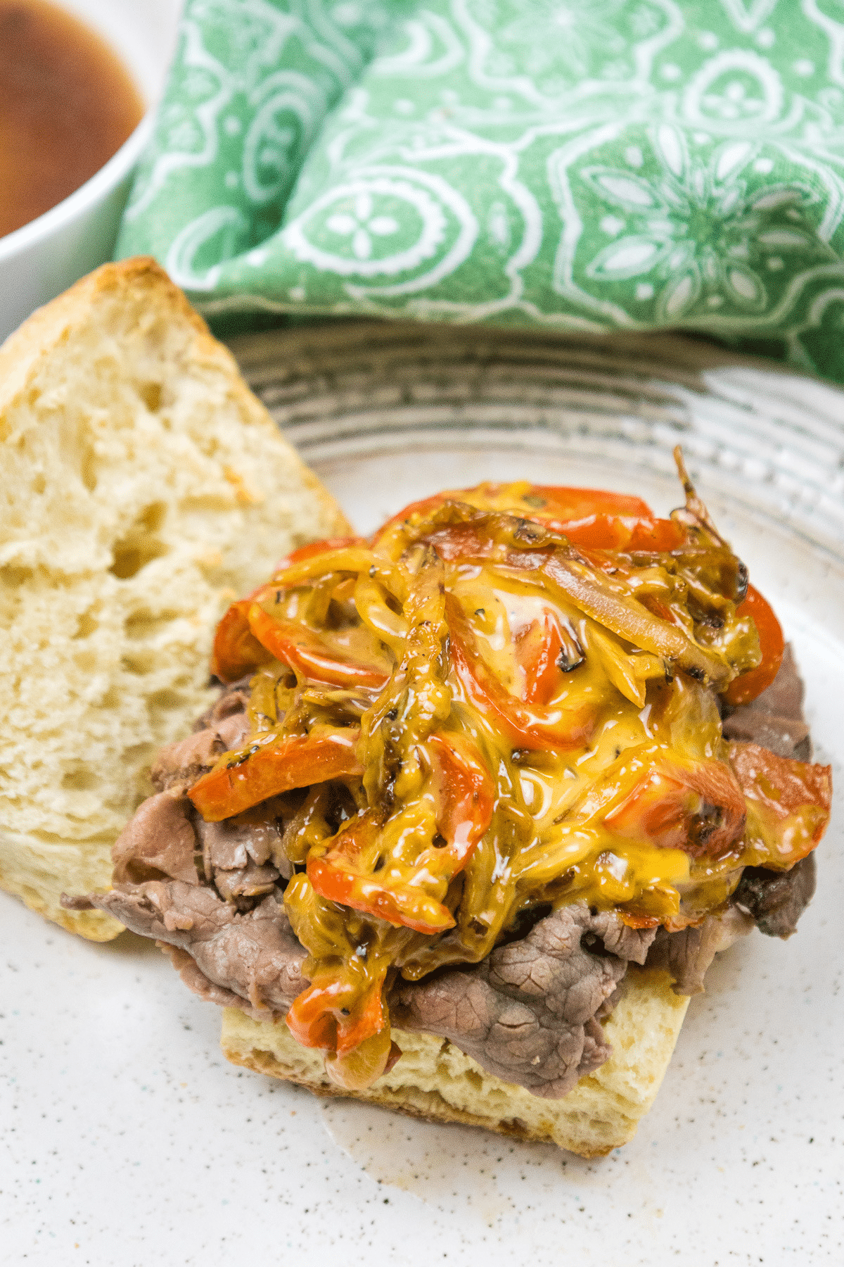 Cheesesteak sandwich without the top bun on a plate.