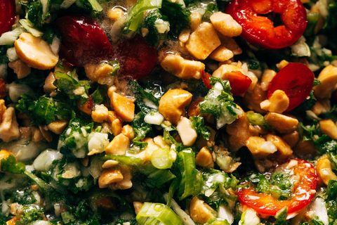 Tossing and massaging the kale and cabbage salad with peanut dressing, peppers, and chopped peanuts